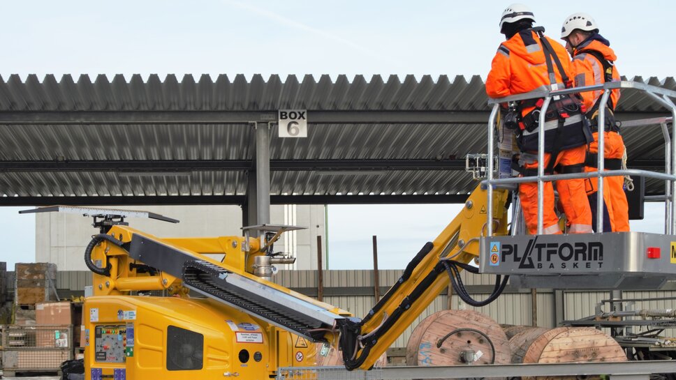 Arbeit mit Zweiwege Steiger zwei Monteure stehen in der Hubarbeitsbühne eines Zweiwege Steigers