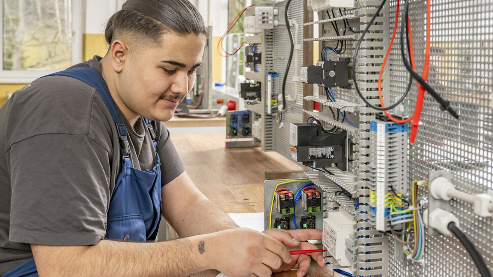 Industrieelektriker Ein auszubildender Industrieelektriker arbeitet an elektrischen Systemen.