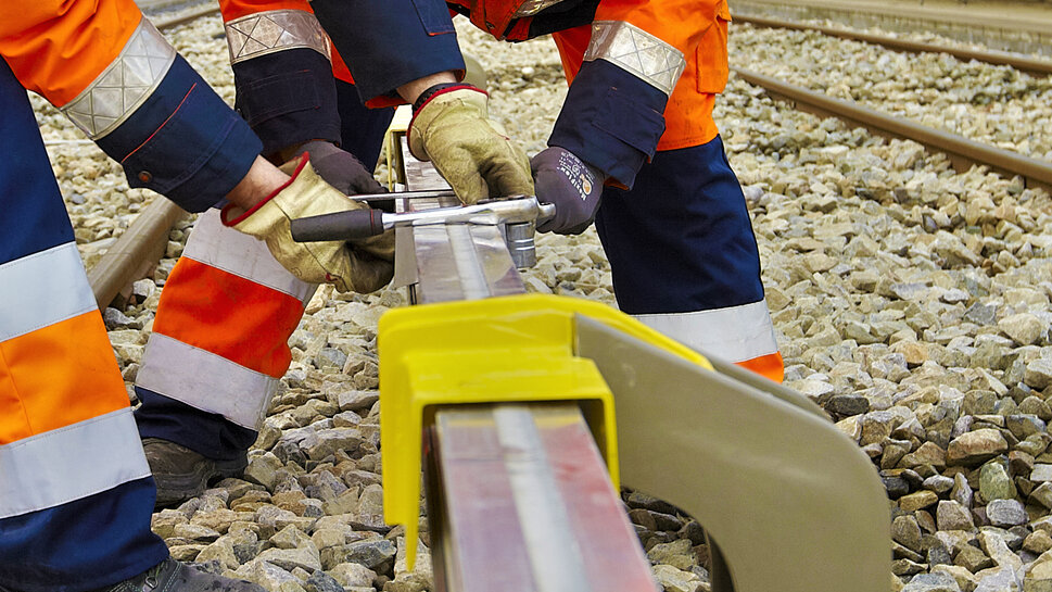 Montagearbeiten an der dritten Schiene Zwei Monteure arbeiten an der dritten Schiene im Nahverkehr/U-Bahn